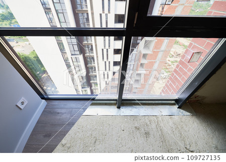 Comparison of living room with large panoramic windows before and after restoration or refurbishment. Residential apartment building behind window glass. Home renovation concept. 109727135
