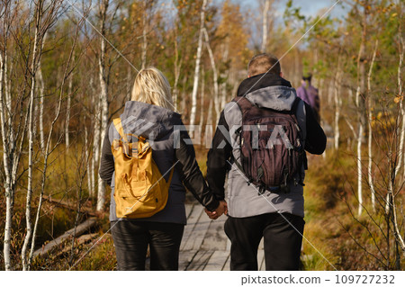 Two tourists walk along a wooden path in a swamp in Yelnya, Belarus 109727232