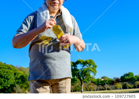 Senior woman drinking strong green tea while walking, Shinryoku Park, diet, exercise, healthy habits, walk 109727605