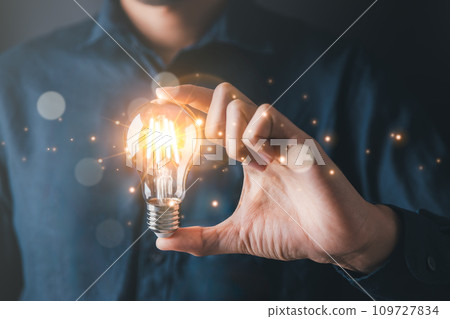 Businessman holding light bulb symbolizing creative idea and strategic thinking in business.Creative solution and idea concept. Businessman holding light bulb symbolizing creative idea and strategic thinking in business.Creative solution and idea concept. 109727834