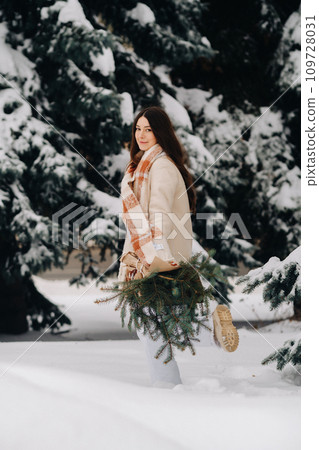 A girl in a winter forest with a bouquet of fir branches. Snowy winter A girl in a winter forest with a bouquet of fir branches. Snowy winter 109728031