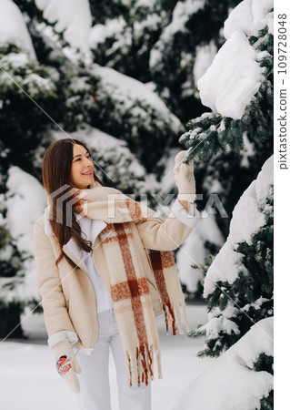 Portrait of a girl with long hair in mittens in a winter forest . Snowy winter Portrait of a girl with long hair in mittens in a winter forest . Snowy winter 109728048