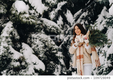 A girl in a winter forest with a bouquet of fir branches. Snowy winter A girl in a winter forest with a bouquet of fir branches. Snowy winter 109728049
