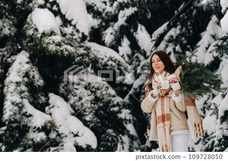 A girl in a winter forest with a bouquet of fir branches. Snowy winter A girl in a winter forest with a bouquet of fir branches. Snowy winter 109728050