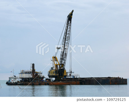a large floating dredging excavator on sea coast a large floating dredging excavator on sea coast 109729125