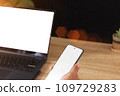 Touch screen mobile phone in hand and laptop computer  109729283