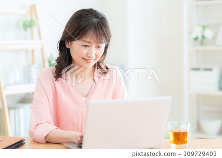 Middle-aged woman teleworking in the living room Middle-aged woman teleworking in the living room 109729401