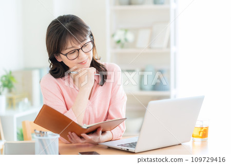 Middle-aged woman teleworking in the living room Middle-aged woman teleworking in the living room 109729416