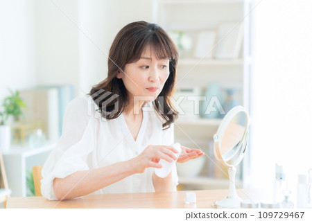 Middle-aged woman doing skin care in the living room Middle-aged woman doing skin care in the living room 109729467