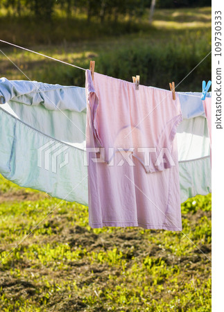 Clean washed laundry hanging on the rope outdoors. Clean washed laundry hanging on the rope outdoors. 109730333