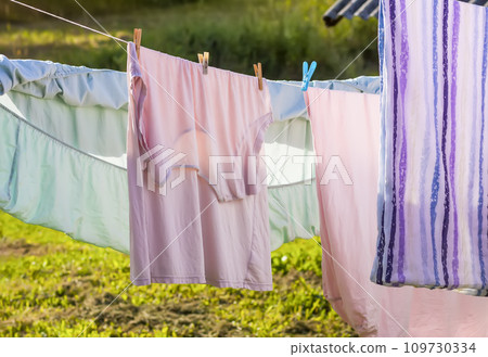 Clean washed laundry hanging on the rope outdoors. Clean washed laundry hanging on the rope outdoors. 109730334