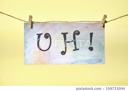 uh lettering on colored paper hanging in front of a yellow background with a rope and clothespins 109733094