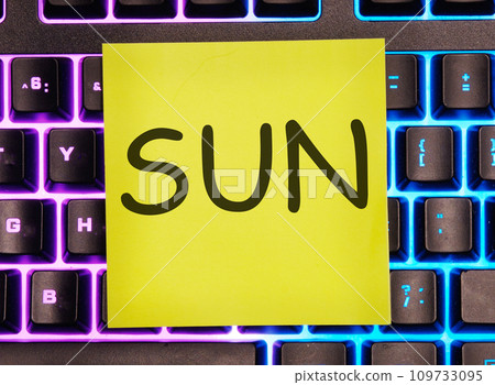 sun written on a yellow sticker on a laptop keyboard with backlight 109733095