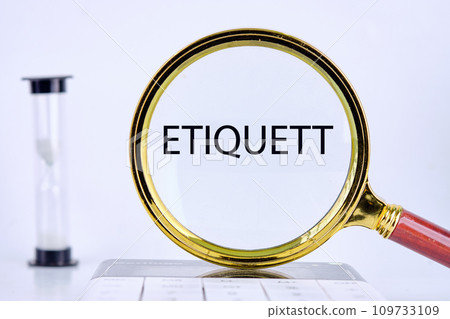 ETIQUETT text, word, inscription found through a magnifying glass next to an hourglass on a light background 109733109