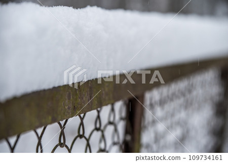 Iron fence covered by fluffy snow 109734161