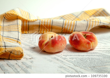 Two saturn peaches or flat peach on white wooden background.. Two saturn peaches or flat peach on white wooden background.. 109735100