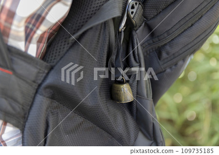 A bear bell attached to a black backpack A bear bell attached to a black backpack 109735185