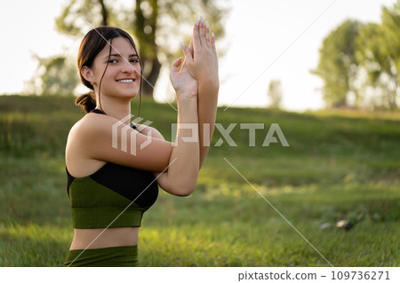 The concept of master classes and seeds. Girl smiling at the camera performing yoga exercises on the background of summer nature The concept of master classes and seeds. Girl smiling at the camera performing yoga exercises on the background of summer nature 109736271