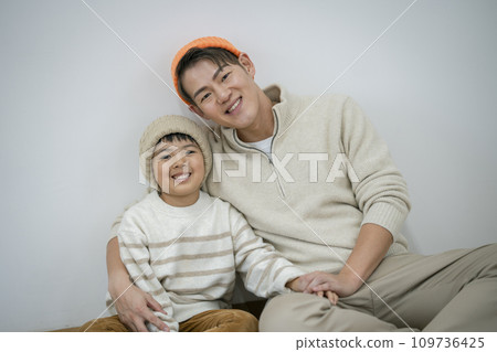 Portrait of a father in his 30s and his 7-year-old son smiling at the camera 109736425