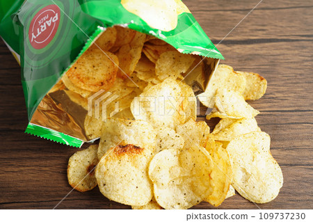 Bangkok, Thailand - May 15, 2022 Potato chips in open bag, delicious BBQ seasoning spicy for crips, thin slice deep fried snack fast food in open bag. 109737230