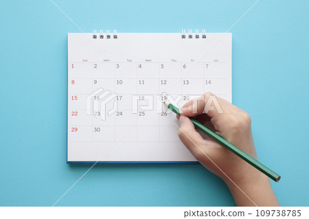 Hand with pencil mark on calendar date 109738785