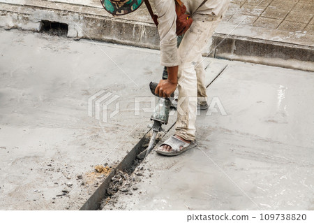Construction worker using jackhammer drilling concrete surface Construction worker using jackhammer drilling concrete surface 109738820