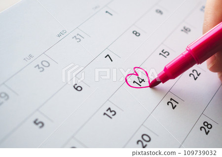 Female Hand with pen mark heart shape on calendar date at 14th valentine day 109739032