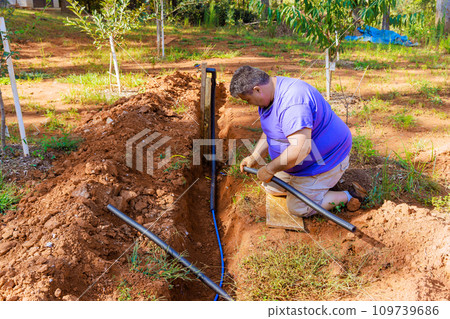 Underground PVC water pipe is thermally insulated with PE foam coated by plumber 109739686