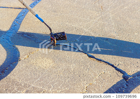 Course of worker patching are filled, asphalt cracks are sealed, bitumen emulsion is applied to restore road surface. 109739696