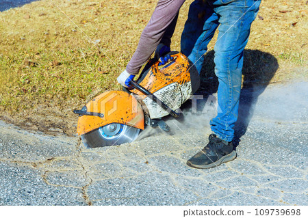 Cutting damaged asphalt cracks before installing new asphalt is an important part of road restoration 109739698