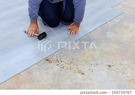 Construction worker installing vinyl laminate flooring in room to new home Construction worker installing vinyl laminate flooring in room to new home 109739767