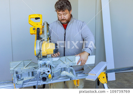Cutting base moldings with chop saw is task performed by trim worker Cutting base moldings with chop saw is task performed by trim worker 109739769