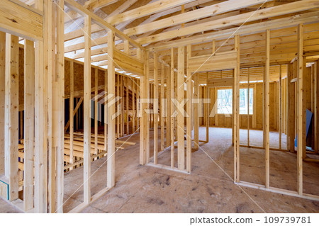 View interior of new house under construction showing incomplete wood framing beams View interior of new house under construction showing incomplete wood framing beams 109739781