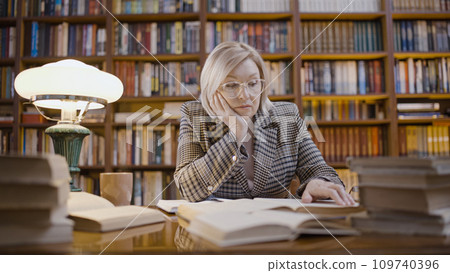 Mature woman tired from overtime work in the library, a journalist studying archives 109740396