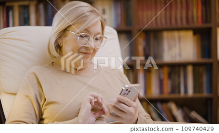 Smiling senior woman texting on her smartphone, online communication, the digital age Smiling senior woman texting on her smartphone, online communication, the digital age 109740429