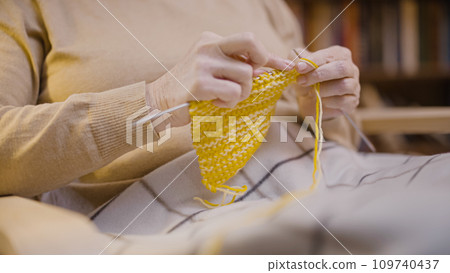 Close-up of a woman knitting a scarf, handmade clothes, a senior person's hobby 109740437