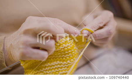 Close-up of the hands of a senior woman knitting at home, her hobby after retirement Close-up of the hands of a senior woman knitting at home, her hobby after retirement 109740440