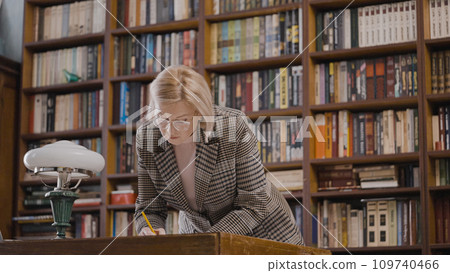 Female researcher working with historical archives in a library late at night 109740466