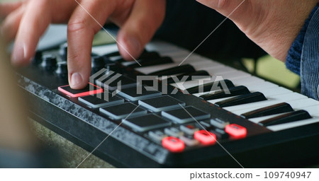 Male musician playing MIDI keyboard and moving rhythmically 109740947
