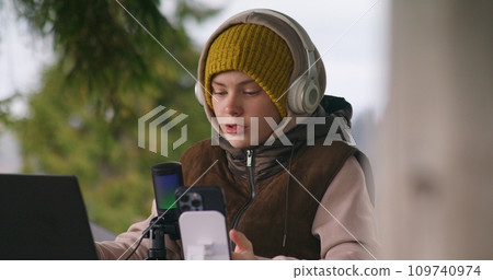 Teenager sits in wooden gazebo and surfs internet during holidays 109740974