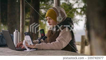 Young streamer uses laptop and phone on tripod for streaming 109740977