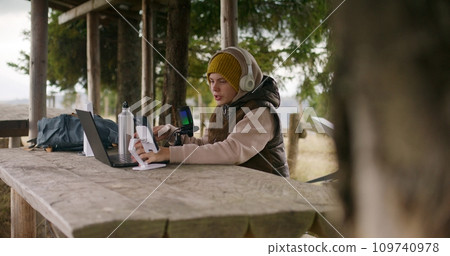 Young streamer sits in gazebo and talks into microphone 109740978