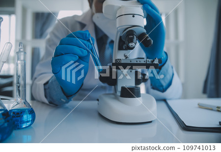 biochemical research scientist team working with microscope for coronavirus vaccine development in pharmaceutical research labolatory, selective focus 109741013