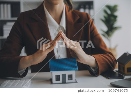 Female hands saving small house with a roof 109741075