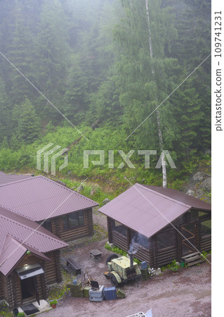 Military field kitchen on wheels near buildings in the forest in the fog Military field kitchen on wheels near buildings in the forest in the fog 109741231