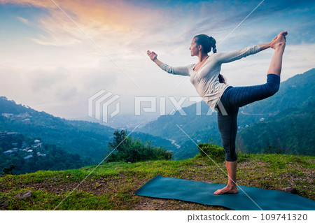 Woman doing yoga asana Natarajasana outdoors at waterfall 109741320