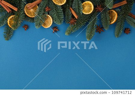 Christmas blue background with fir tree, dried orange, cinnamons and star anise. Top view with copy space for your text Christmas blue background with fir tree, dried orange, cinnamons and star anise. Top view with copy space for your text 109741712