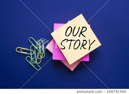 Our story symbol. Orange steaky note with words Our Story. Beautiful deep blue background. Business and Our story concept. Copy space. 109742304