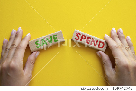 Save or Spend symbol. Concept word Save or Spend on wooden blocks. Businessman hand. Beautiful yellow background. Business and Save or Spend concept. Copy space Save or Spend symbol. Concept word Save or Spend on wooden blocks. Businessman hand. Beautiful yellow background. Business and Save or Spend concept. Copy space 109742743