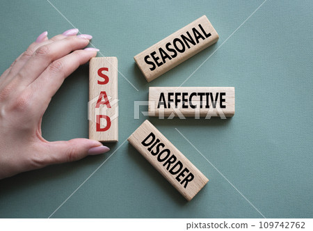 Sad - Seasonal Affective Disorder symbol. Wooden blocks with words Sad. Businessman hand. Beautiful grey green background. Business and Sad concept. Copy space. 109742762